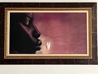 Framed painting showing a profile of a face with a white butterfly near the lips, in a dark maroon background with a decorative brown and gold frame.