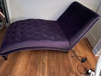 Side view of royal purple chaise lounge showing tufted fabric and studded trim