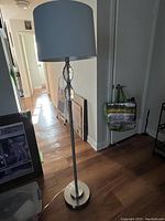 Full view of the crystal balled floor lamp showing silver base, pole, white cylindrical lampshade and crystal ball accents in hallway setting.