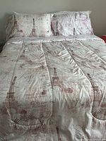 Full bed setup with Parisian Eiffel Tower and Paris script print comforter and matching pillow shams on a queen size bed.