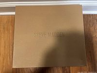 Steve Madden branded brown box lid with embossed logo.