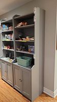 Frontal view of grey bookcase showing three open shelves and lower cabinet doors