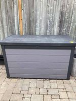 Front view of closed deck box against fence