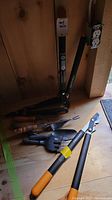 Full view of the complete set of different Fiskars garden hand tools on a wooden surface, showing handles and pruner blades.