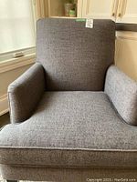Front view of gray fabric armchair showing overall shape and cushion