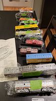 Long view of approximately 16 HO scale train cars individually wrapped and displayed on a table