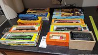 Overview of eight HO scale boxed items on countertop showing mixed brand locomotives and gondola