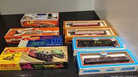 Overview of boxed model trains and train cars from various brands placed on a table.