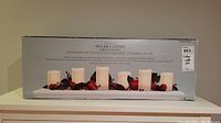 Photo of the product box showing the set of six pillar candle string lights with decorative garland on a white base.