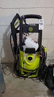 Front view of Sunjoe SPX3000 electric pressure washer showing green body, detergent bottle attached, and power cord coiled at the base.