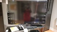 Samsung 46-inch LCD TV on glass stand with two Samsung remote controls and a note.