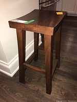 Side angle of the wooden stool showing the full structure including legs and support bars.