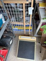 Acuvibe foot massager on the floor with wooden adjustable width gate behind it.