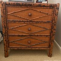 Front view of wicker end table showing three woven drawers and mottled wood frame