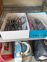 Two boxes containing mixed flatware including forks, spoons, and knives with ornate handles.