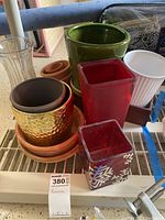 Overview of assorted planters showing different types of pots and containers including ceramic, glass, and terracotta with visible wear and dust indicating used condition