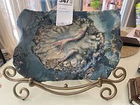 Front view of the raku pottery plate mounted on metal stand, showing glaze colors and texture.