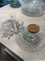 Shot glasses, platter, jar, and candle holders on countertop