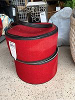 Red cylindrical zippered carrying case showing zippers and overall shape