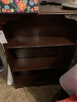 Front view of wooden bookshelf showing three shelves and visible scratches.
