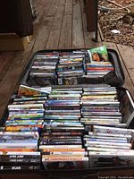 Photo of an open suitcase packed with DVDs showing a variety of movie titles stacked vertically in rows.