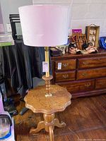 Full view of oak finish lamp table with lamp on top, showing wood grain and room background.
