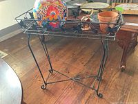 Black metal plant stand with leaf design top and curled leg details
