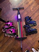 Photo shows two pairs of in-line skates on either side of a pogo stick on a wooden floor.