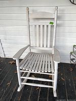 Full front view of white wooden rocking chair against white wall, showing overall condition and design.
