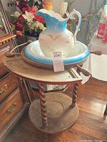 Overview of wooden wash basin stand holding two pitcher and basin sets with visible cracks and missing top piece on stand