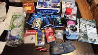Photo showing a variety of items including boxed IP camera, NHL games, car bulbs, motor part, a polishing cloth, candles, pinwheel with pins, and a tire rim.