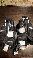 Pair of black Bauer hockey gloves showing front with palms up, brand tags visible.