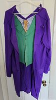 Purple Joker style coat with attached green vest and tan shirt detail hanging on a hanger.
