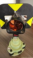 Front view of Leica GPR121 single reflective prism with yellow and black target plate and glass prism elements.
