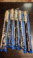 Five brand new plastic recorders sealed in individual clear plastic packaging with blue backing, with beige top mouthpiece and black upper/middle/lower body sections.