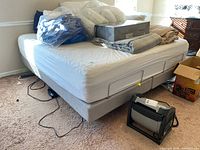 Overall view of king adjustable bed frame with mattress and bedding piled on top