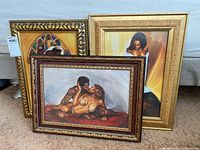 Three framed art prints displayed leaning on a wall, varying frame styles and artwork visible