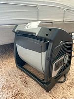 Side and front angle view showing cylindrical fan, control dials and air outlet.