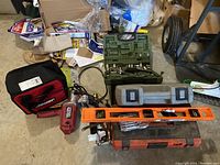 Overall view of the lot showing various toolboxes, a red Bauer tool bag, an orange level, a Chicago Electric power tool, and the green socket set partially visible.
