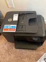 Front left view of HP OfficeJet Pro 8710 showing top cover, input tray, HP logo, and Instant Ink sticker