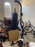 Full view of Everlast punching bag hanging from the black metal stand in a garage setting, showing bag, stand, and surrounding items.