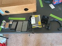 Photo of phones, cases, smart watch charger, small jewelry box and diecast car arranged on table