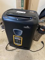 Front view of black Fellowes DS-1400C shredder with power cord on floor and transparent waste bin window.
