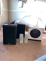 Overview of all speakers: pair of Infinity Xfinity speakers, two white AOpen computer speakers, and Harman/Kardon Onyx Studio wireless speaker with box.