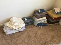 Full lot overview showing stacks of towels and bedding items arranged on carpet against wall.