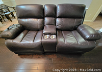 Front view showing both reclining seats, center console with cup holders, and faux leather upholstery