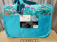 Photo of the folded Mainstays outdoor blanket in a carrying case with a tropical leaf pattern.