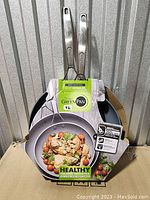 Two GreenPan ceramic nonstick frying pans in original packaging, showing pans and handles with brand label and packaging.