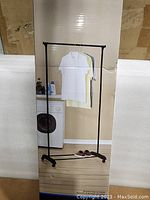 Box image showing printed garment rack with hanging clothes and shoes below, indicating the product type and usage.