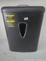 Front view of black Amazon Basics shredder showing transparent window and warning labels.